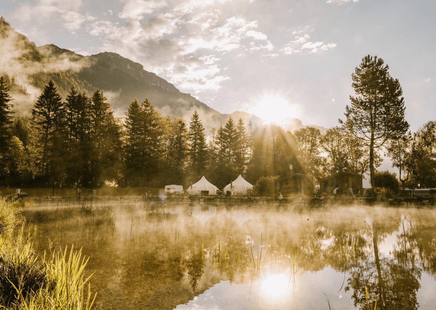 See vom Camping Steinplatte in der Abendsonne mit den Alpen im Untergrund und Glamping Zelten